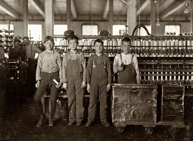 Photo showing: Four Doffers -- November 1908. Lincolnton, N.C. Cotton mill workers at Daniel Manufacturing -- four doffers. Eat when they can. Some of them 'eat a-workin'.