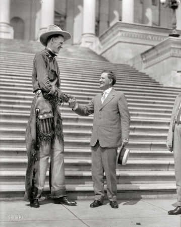 Photo showing: High Politics -- Ralph E. Madsen, the tall cowboy, shaking hands with Senator Morris Sheppard at Capitol, 1919.