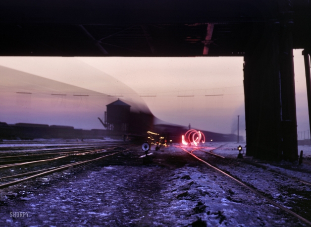 Photo showing: Twilight Departure: 1942 -- Time exposure of brakeman signalling in a departure yard at Chicago & North Western's Proviso yard at twilight.