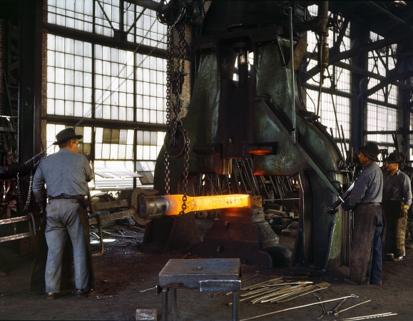 Photo showing: Hammer and Tongs -- March 1943. Santa Fe R.R. shops, Albuquerque. Hammering out a drawbar on the steam drop hammer.
