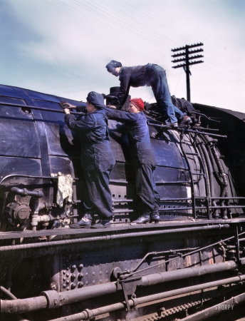Photo showing: On Top of Old Steamy: 1943 -- Chicago & North Western RR, Clinton, Iowa. Women wipers cleaning one of the giant H-class locomotives.