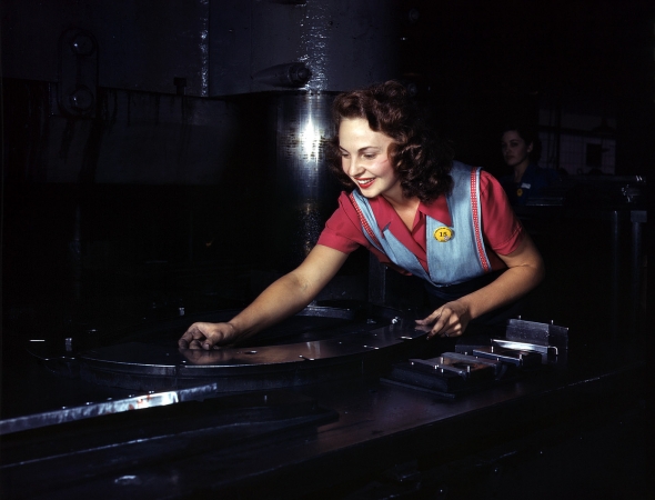Photo showing: Watch the Fingers: 1942 -- Placing parts on Masonite before they slide under the multi-ton hydropress. No. American Aviation, Inglewood, California.