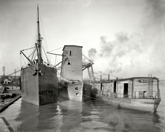 Photo showing: Bread and Water -- New Orleans circa 1906. Steamer loading grain from floating elevator.