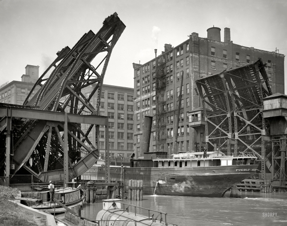 Photo showing: Open Sesame -- Chicago, circa 1907. Jackknife Bridge, Chicago River. The Pueblo passing through the open span.