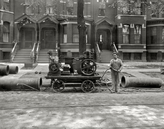 Photo showing: Upstairs, Downstairs -- Probably Detroit circa 1910. Gas Company. Worker with pipes and an air compressor.