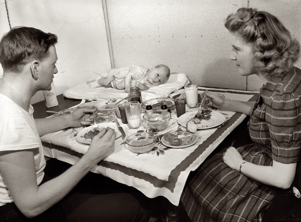 Photo showing: And Baby Makes Three -- Washington, D.C. December 1943. Second class petty officer studying in Washington and his wife eating dinner. 