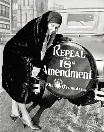 Photo showing: Driven to Drink -- Dec. 16, 1930. Chicago.  The Crusaders have new slogans. Miss Elizabeth Thompson was one of the first
fmembers of that national organization, formed to overthrow Prohibition, to put the new tire cover on her car.