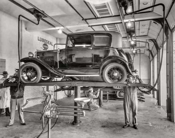 Photo showing: Well-Oiled Machine -- Circa 1930. Ford Model A on lubrication rack at Lubeseal service garage.