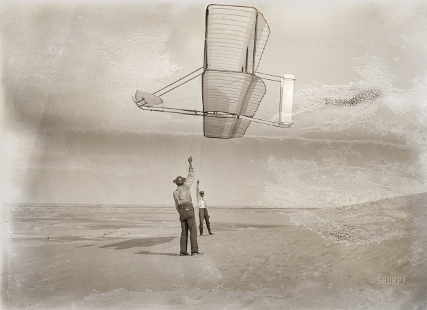 Photo showing: Against the Wind -- Sept. 19, 1902. Kitty Hawk, North Carolina. Dan Tate, left, and Wilbur Wright flying the 1902 glider as a kite.