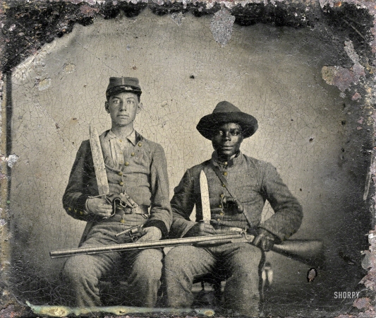 Photo showing: Andy and Silas -- Sgt. A.M. Chandler of the 44th Mississippi Infantry Regiment, Co. F., and Silas Chandler,
family slave, with Bowie knives, revolvers, pepper-box, shotgun, and canteen.