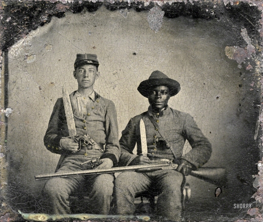 Photo showing: Andy and Silas -- Sgt. A.M. Chandler of the 44th Mississippi Infantry Regiment, Co. F., and Silas Chandler,
family slave, with Bowie knives, revolvers, pepper-box, shotgun, and canteen.