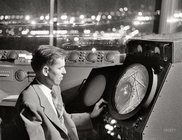 Photo showing: On My Radar -- September 1952. Man in airport control tower looking at radar screen.