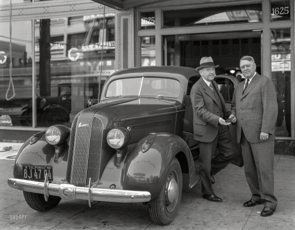 Photo showing: The Handover -- Sept. 3, 1935. Pontiac at H.O. Harrison Co., 1625 Van Ness Avenue, San Francisco. Harrison (right) and Howard.