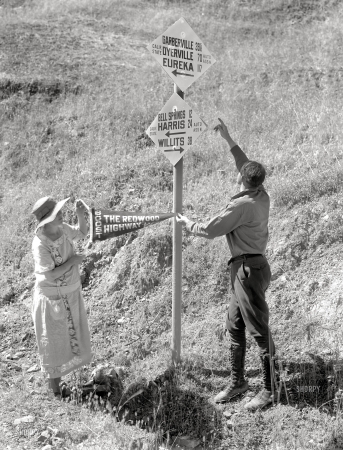 Photo showing: Eureka! -- Circa 1925. Man pointing at California State Automobile Association
signage; woman with pennant reading BOOST THE REDWOOD HIGHWAY.