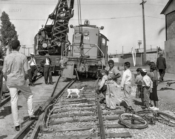Photo showing: Back on Track. -- Richmond, California, circa 1957. Crane hoisting a yard switcher that got derailed.