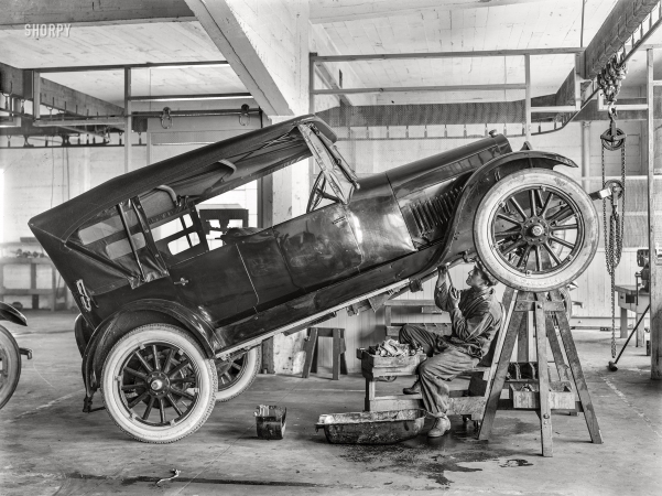 Photo showing: Jacked Up -- San Francisco circa 1915. Garage mechanic and Studebaker.