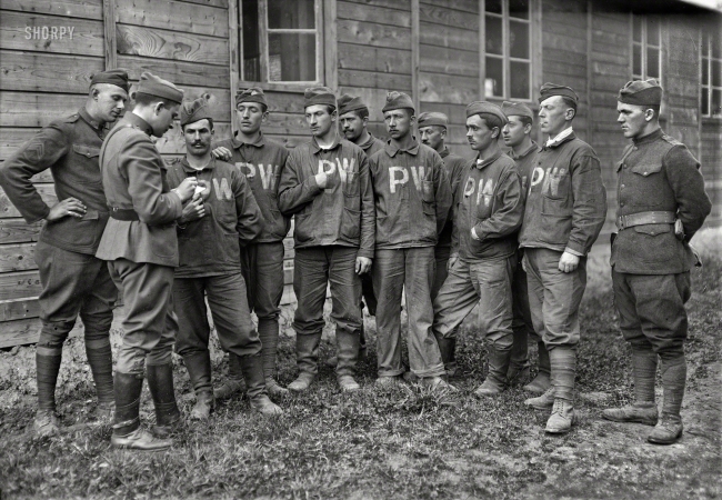 Photo showing: Prisoners of War -- October 30, 1918. Base Hospital No. 7 at Tours, France. American Red Cross Chaplain the Rev. F.M. Eliot
taking the home addresses of interned German prisoners, so that their families may be notified that they are well.
