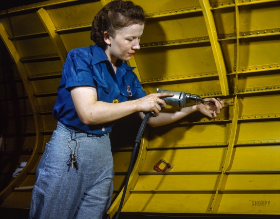 Photo showing: True Blue -- February 1943. Operating a hand drill at Vultee-Nashville, this woman is working on a 'Vengeance' dive bomber.
