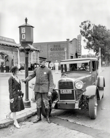 Photo showing: Stop-and-Go -- San Francisco, 1927. Traffic signals -- police officer stops pedestrian
crossing against the light in front of Hudson sedan at Bee Garage.