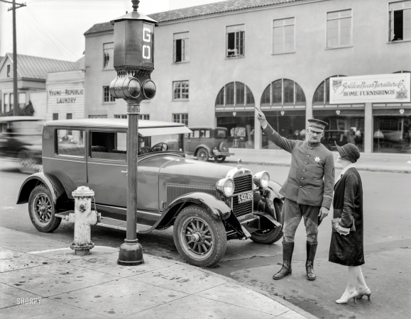 Photo showing: Go Means Stop -- San Francisco, 1927. Traffic signals -- police officer stops pedestrian crossing against the light.