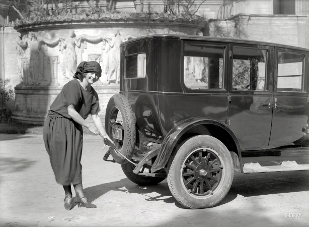 Photo showing: Gun Moll -- San Francisco, 1924. Woman greasing Oldsmobile sedan.