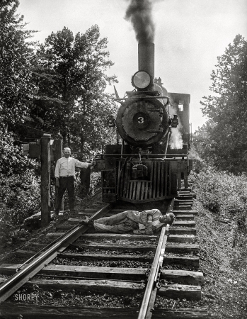 Photo showing: Dude on the Tracks -- June or July 1926. Washington, D.C., or vicinity. Man lying in front of train on tracks.