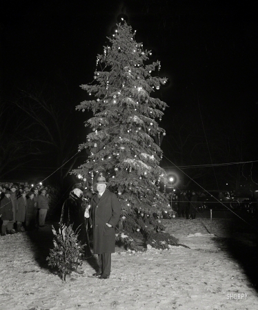 Photo showing: Electric Xmas -- Dec. 24, 1929. President Hoover pressed the button that set the community Christmas tree
of the National Capital ablaze with varied colored lights tonight, Christmas Eve, accompanied
by Mrs. Hoover while members of the Cabinet and other high officials looked on.