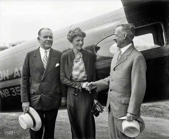 Photo showing: Amelia Earhart -- June 1932. Washington, D.C. Aviator Amelia Earhart Putnam being greeted by
Drs. Gilbert Grosvenor, right, and John Oliver la Gorce of the National Geographic Society.
