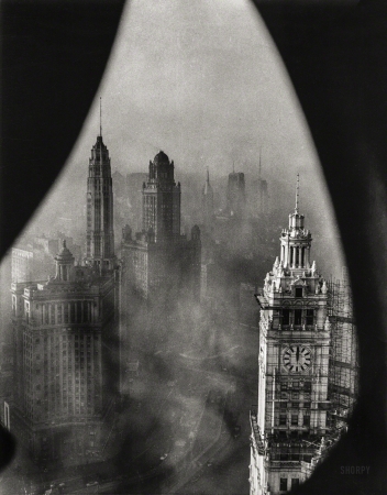 Photo showing: Low Noon -- Nov. 1, 1952. Chicago framed by Gothic stonework high in the
Tribune Tower.. View shows low-lying smog which blanketed the area
one recent morning. In the foreground is the well-known Wrigley Building.