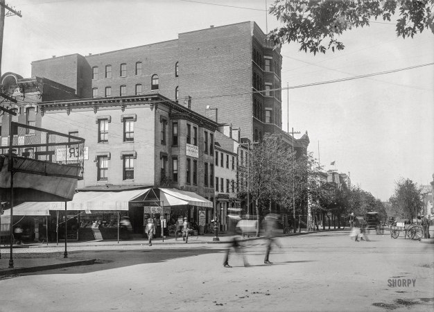 Photo showing: This Desirable Corner -- Washington, D.C., circa 1901. View of E Street N.W., south side, looking west from Seventh Street towards Eighth.