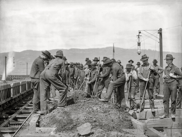 Photo showing: Earth Movers -- Washington, D.C., or vicinity circa 1901. Group of laborers on railcar digging through dirt pile along track bed.