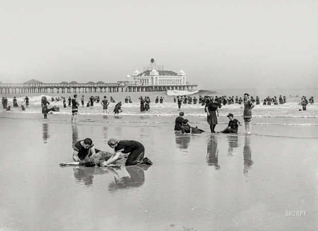 Photo showing: Buried at Seashore -- Atlantic City, New Jersey, circa 1905. Beach bathers and Steel Pier.