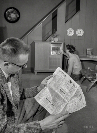 Photo showing: Radio Highlights -- December 1957. Washington, D.C. Man with broadcast listings; woman tunes radio.