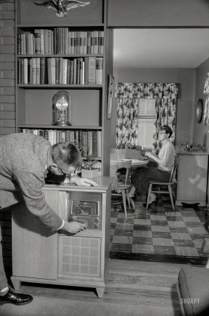 Photo showing: Do Touch That Dial -- December 1957. Washington, D.C. Man tuning console radio while woman in next room types.