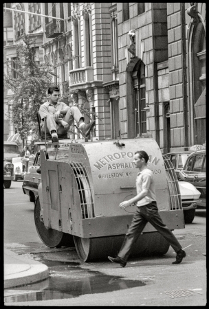 Photo showing: The Flattenator II -- July 1964. New York. Man walking in front of construction worker driving asphalt paver.