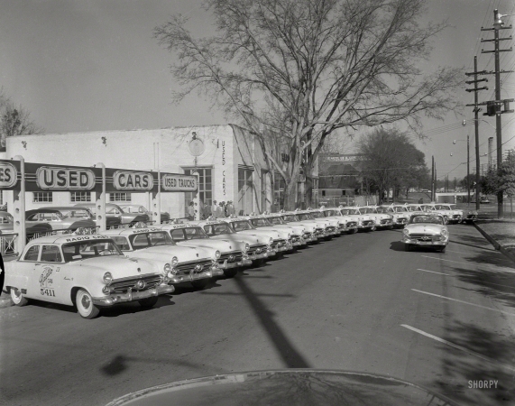 Photo showing: Service in a Flash -- Columbus, Ga., circa 1952. Radio Cab Co. A fleet of two-door taxis -- Ford Mainline Tudor Sedans.