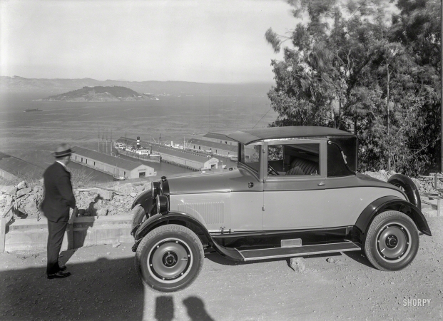 Photo showing: Pier 23 -- 1925. REO coupe overlooking San Francisco Bay, Embarcadero piers and Yerba Buena Island.