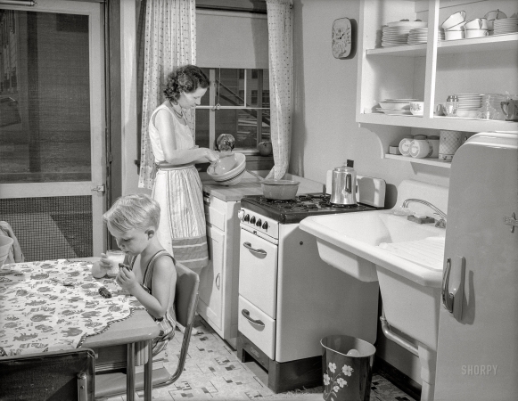 Photo showing: War Kitchen. -- July 1941. War housing. Mrs. B.J. Rogan and her small son, Bernie, in the kitchen
of their new war home at the Franklin Terrace housing project in Erie, Pennsylvania.