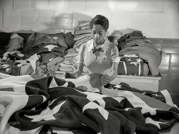 Photo showing: Stars and Stripes. -- May 1942. Philadelphia Quartermaster Corps. The tradition of Betsy Ross is being kept alive in this Quartermaster
Corps depot, where a young woman worker assists in the creation of American flags for military activities.