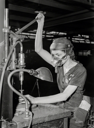 Photo showing: Lever of Power -- August 1942. Eunice Hancock, 21, operates a compressed-air grinder in a Midwest aircraft motor plant.