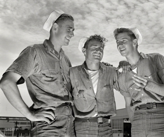 Photo showing: Jokey Salts -- August 1942. Sailor mechanics at the naval air base in Corpus Christi, Texas,
laugh heartily over a good story between servicing operations on Navy planes.