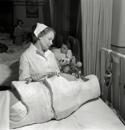Photo showing: Plastered -- November 1942. Babies' Hospital, New York. Nurse attending patient in a corrective cast.