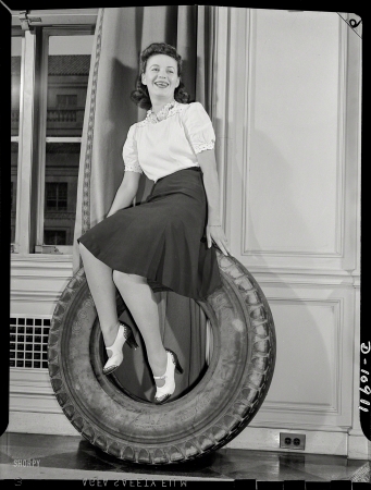 Photo showing: On a Roll -- July 1942. Miss Jean Spanitz, stenographer in the
Division of Motor Transportation, poses with truck tire. 