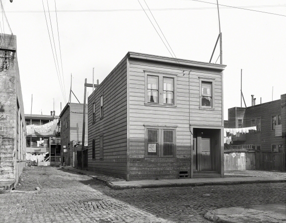 Photo showing: Lilac Street -- February 1936. Lilac Street, Mission District, San Francisco. Rent fifteen dollars a month for three rooms.