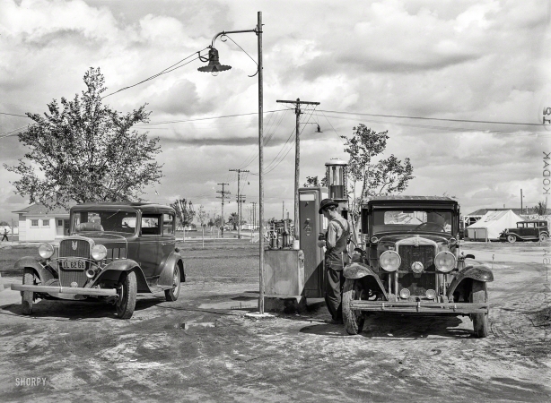 Photo showing: A Tale of Two Chevys -- March 1940. Cooperative gas station at Shafter migrant camp. Shafter, California.