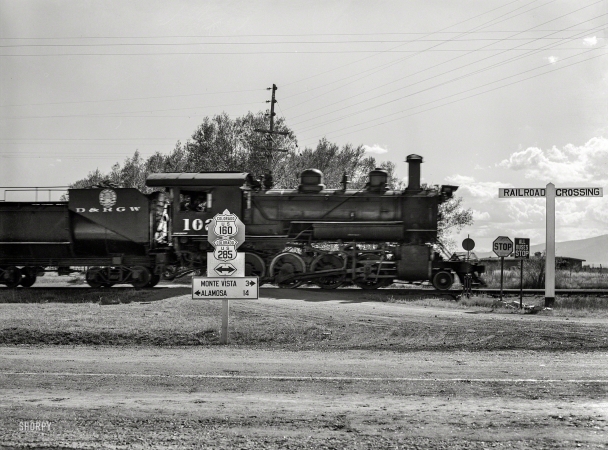 Photo showing: Denver and Rio Grande -- October 1939. Railroad crossing. Rio Grande County, Colorado. Locomotive of Denver & Rio Grande Western R.R.