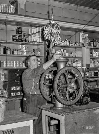 Photo showing: Batteries to Bananas -- October 1939. Grinding coffee. General store selling everything from batteries to bananas in Lamoille, Iowa.