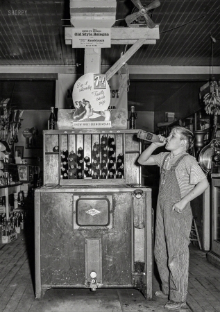Photo showing: Sip It Slowly -- October 1939. Farm boy at pop stand. General store in Lamoille, Iowa.