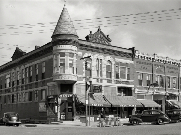 Photo showing: DRUGS SODA -- October 1939. Stores on main street (G Avenue). Grundy Center, Iowa.