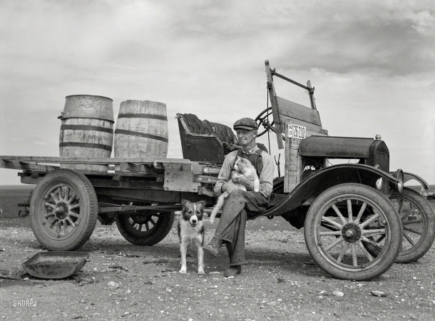 Photo showing: With Both Barrels -- September 1937. Herman Gerling, farmer. Barrels on truck are for hauling spring water. Near Wheelock, North Dakota.